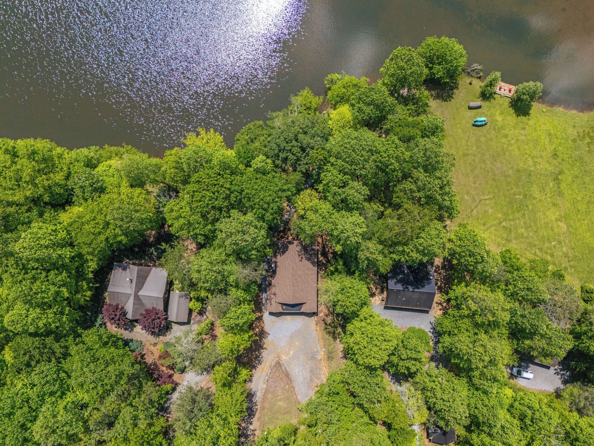An aerial view of a residential area with houses surrounded by dense greenery and a lake.