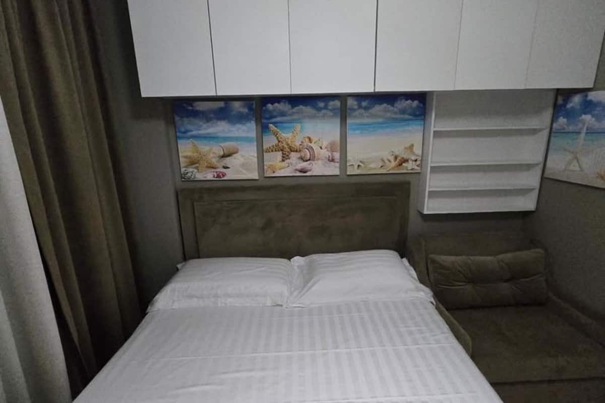 A bedroom with a bed, a headboard with a beach-themed mural, and a large wardrobe above the bed.