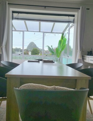 A modern kitchen with a large island, a dining area with chairs, and a view of a mountain through large windows.