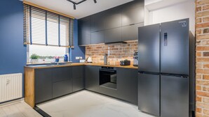 Una cocina moderna con refrigerador de acero inoxidable, horno empotrado y un salpicadero de ladrillo.