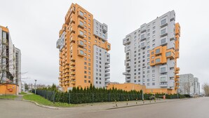 Dos edificios residenciales altos con balcones, rodeados por una cerca y follaje.