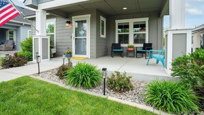 A modern house with a covered porch, outdoor seating, and a flag. - Boutique CDA Retreat | Sleeps 6 • Near Downtown (Coeur d'Alene)