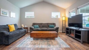 A living room with two sofas, a coffee table, a TV, and a fireplace. - Boutique CDA Retreat | Sleeps 6 • Near Downtown (Coeur d'Alene)