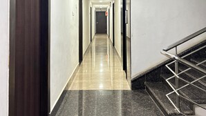 A long, narrow hallway with a polished floor, a staircase on the right, and doors on the left.