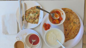 A table with a plate of food including a slice of pizza, a bowl of soup, and a cup of coffee.