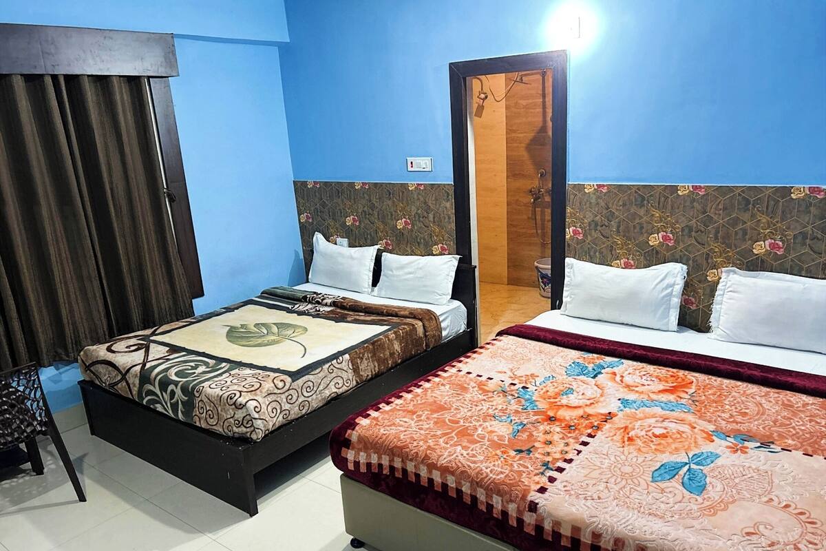 A hotel room with two beds, a wooden door, and a curtain.