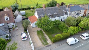 A rural house with a large garden, a driveway, and a road with parked cars. - Countryside Cottage in Bulmer- Sleeps 6/7 (Sudbury)