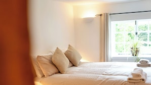 A neatly made bed with a quilted cover, two pillows, and a stack of folded towels. - Countryside Cottage in Bulmer- Sleeps 6/7 (Sudbury)