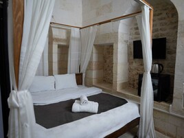 Una cama con dosel con sábanas blancas, un colchón oscuro y una toalla blanca sobre la cama.