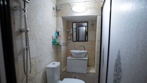 Un baño pequeño con inodoro, lavamanos y ducha.