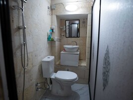 Un baño pequeño con inodoro, lavamanos y ducha.