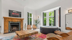 A modern living room with a fireplace, a Netflix TV, a hot tub, and a colorful rug. - Charming,Spacious Manor House with Lake&Pool Table (Blakedown)