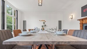 A modern dining room with a long table, cushioned chairs, and a fireplace. - Charming,Spacious Manor House with Lake&Pool Table (Blakedown)