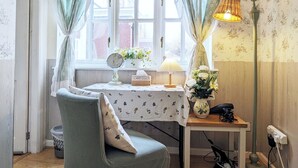 Una habitación acogedora con ventana, una mesa con espejo, una lámpara y una silla.