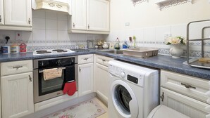 Una cocina con armarios blancos, estufa, horno y lavadora.