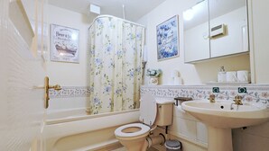 Un baño con bañera, inodoro, lavabo y espejo.