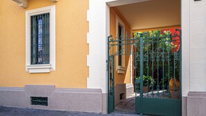 A yellow building with white trim, a balcony with a wrought iron railing, and a green gate. - Accomodo MIB13 Bivano Navigli (Milan)