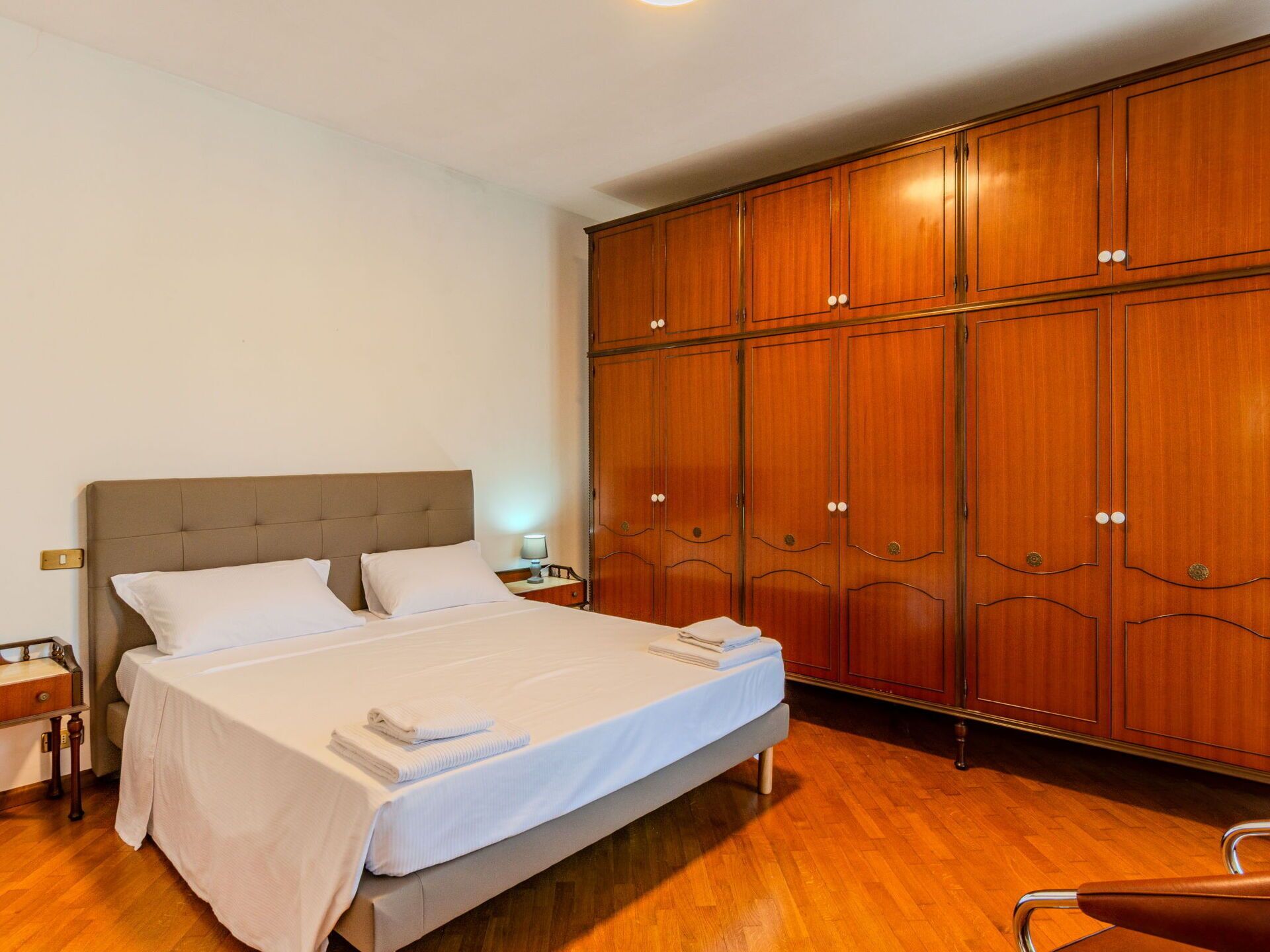 Ein Hotelzimmer mit einem großen Bett, einem Holzschrank und Holzboden.