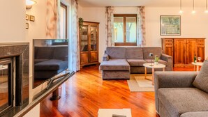 A living room with a TV, two sofas, a cabinet, and a window with curtains.