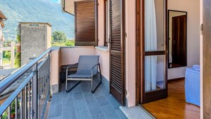 A balcony with a chair, a wooden door, and a view of mountains.