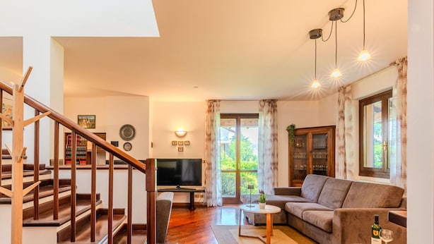 A living room with a wooden staircase, a sofa, a coffee table, and a television.