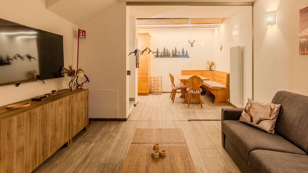 Ein modernes Wohnzimmer mit Flachbildfernseher, Holzmöbeln und einer gemütlichen Sitzecke.