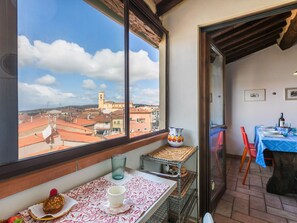 A balcony with a table set for dining, a view of a town, and a window with a view of buildings. - Nice apartment for 4 people with WIFI, balcony and pets allowed (Rosignano Marittimo)