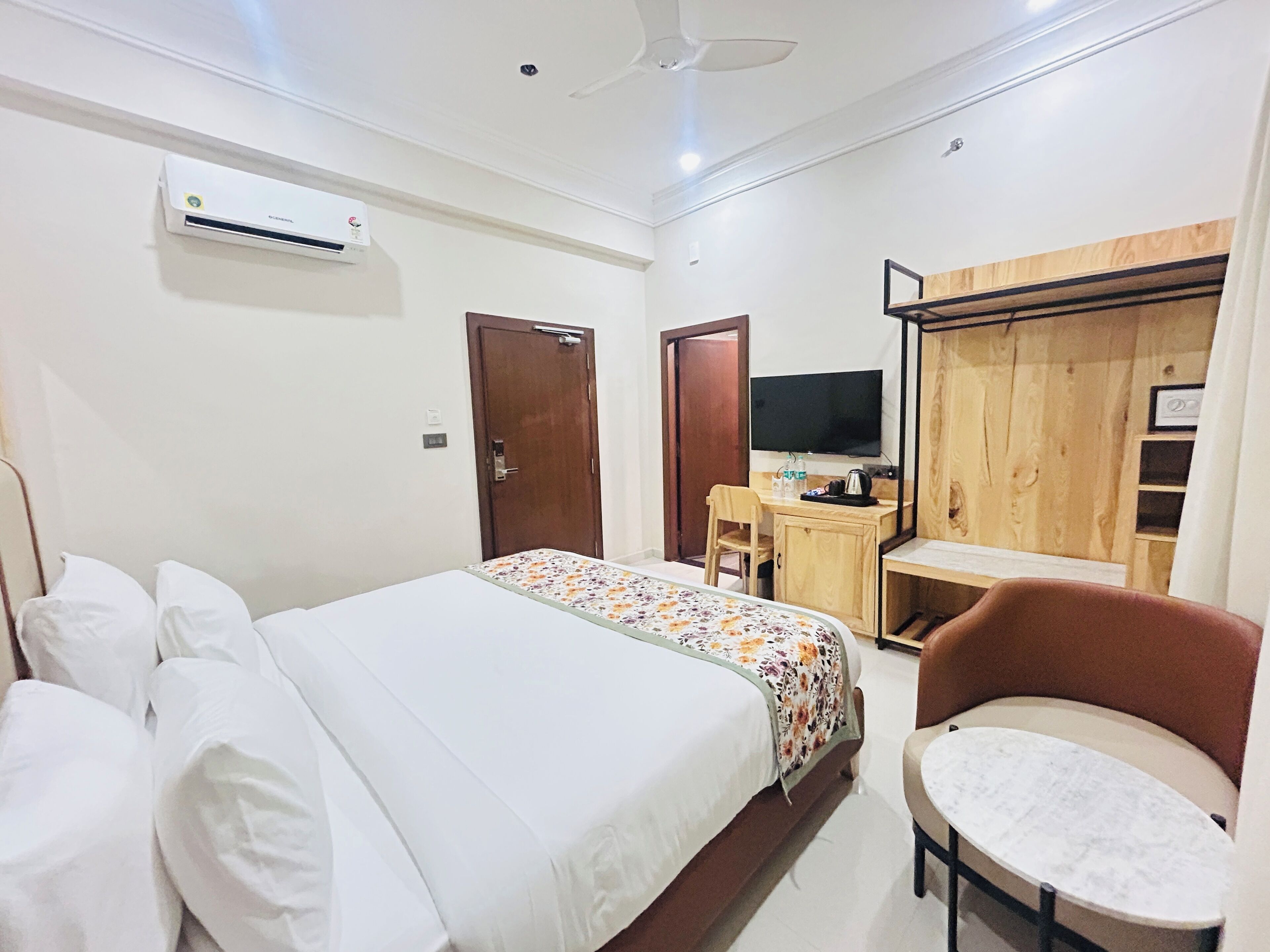 A hotel room with a bed, a desk, a chair, a TV, and a wardrobe.