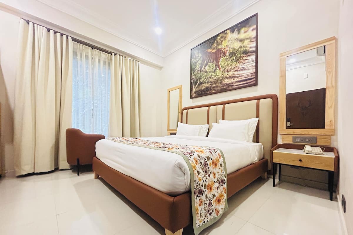 A hotel room with a large bed, a desk with a computer, a chair, and a painting of a tiger on the wall.