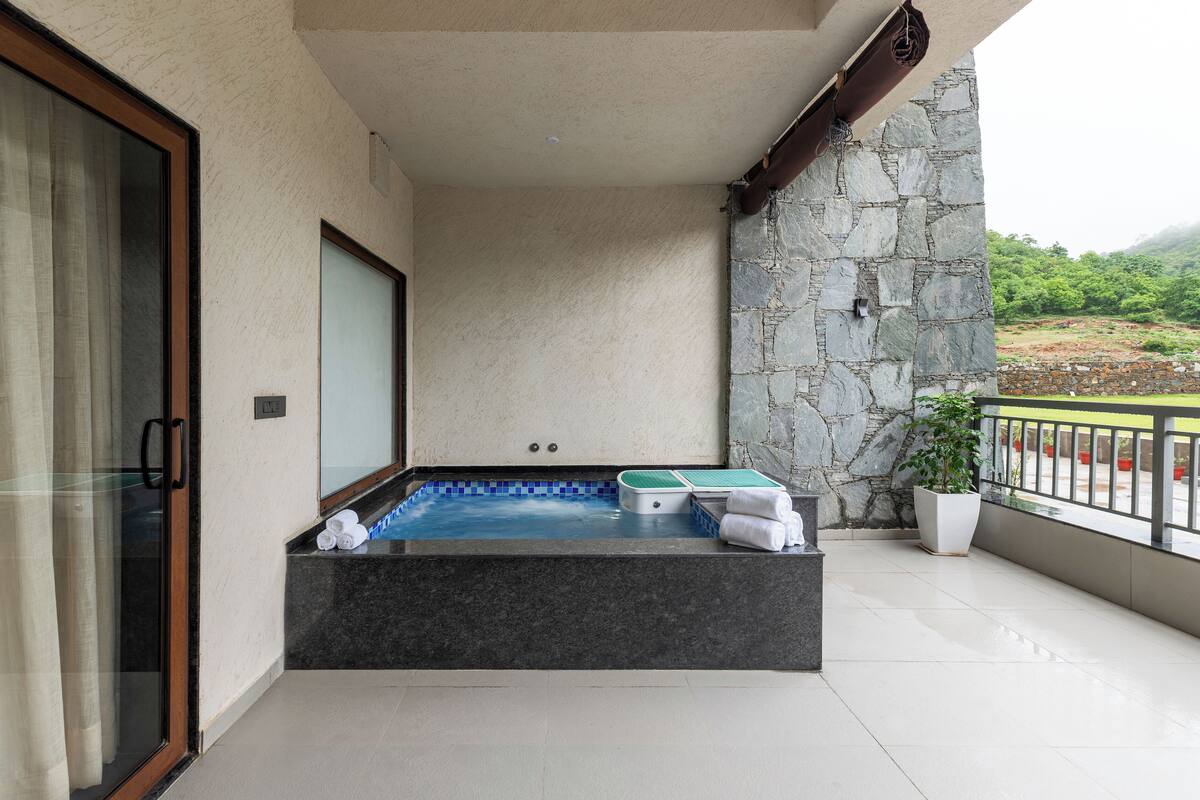 A spa area with a hot tub, towels, and a potted plant.