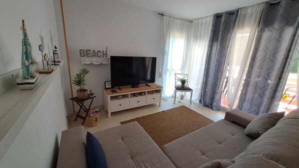 Una sala de estar con un sofá, un televisor, una mesita con una planta y un cartel que dice "BEACH".