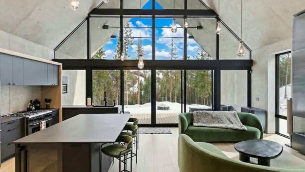 A modern kitchen with a large island, dining area with chairs, and a green sofa. - Luxury Home | Ski In / Ski Out | 5 Bed / 4 Bath (Whitefish)