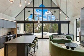 Una cocina moderna con una isla grande, comedor con sillas y un sofá verde.