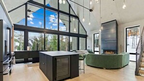 A modern kitchen with a large island, a fireplace, and a view of the outdoors. - Luxury Home | Ski In / Ski Out | 5 Bed / 4 Bath (Whitefish)