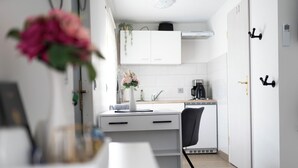 Cocina moderna con armarios blancos, una silla negra y un florero con flores en la encimera.