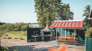 Una cocina al aire libre de piedra con chimenea, un banco y una mesa.