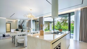 Una cocina moderna con una isla central, ventanas amplias y vistas al verdor exterior.