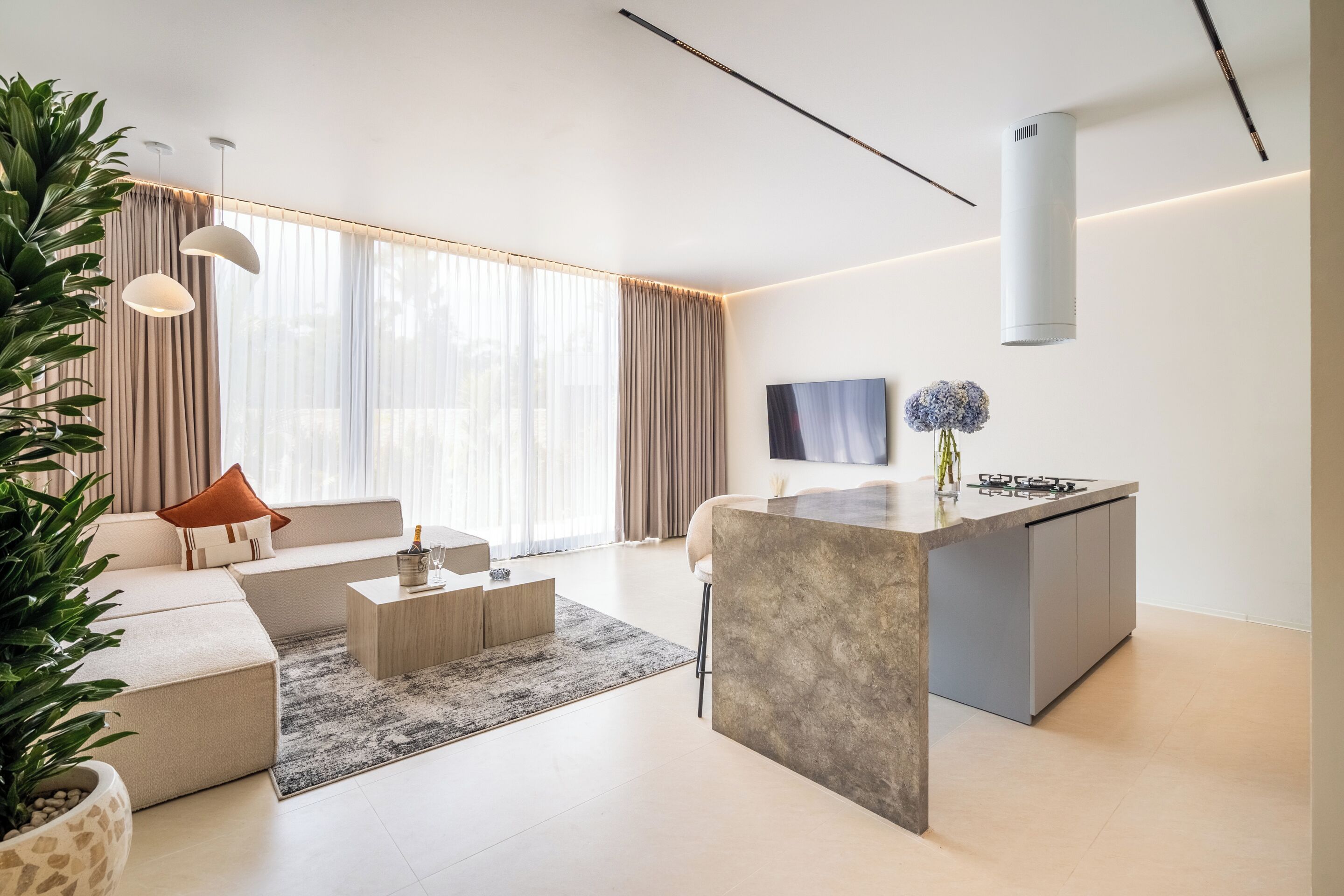 A modern living room with a sofa, coffee table, and a kitchen island with a built-in stove.