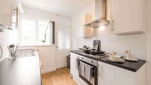 A modern kitchen with white cabinetry, a black countertop, and a window providing natural light. - Double Bedroom in Budget Friendly Shared House (Doncaster)