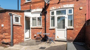 A red brick house with a satellite dish, a white door, and a small patio with a table and chairs. - Double Bedroom in Budget Friendly Shared House (Doncaster)
