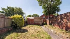 A backyard with a brick wall, a wooden fence, and a tree.