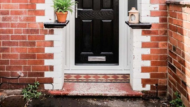 A brick building with a black door, white archway, and a small potted plant on the left. - Convenient Budget Room in Shared House w Kitchen (Doncaster)
