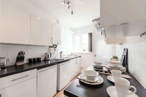 A modern kitchen with white cabinets, a black countertop, and a window providing natural light. - Convenient Budget Room in Shared House w Kitchen (Doncaster)