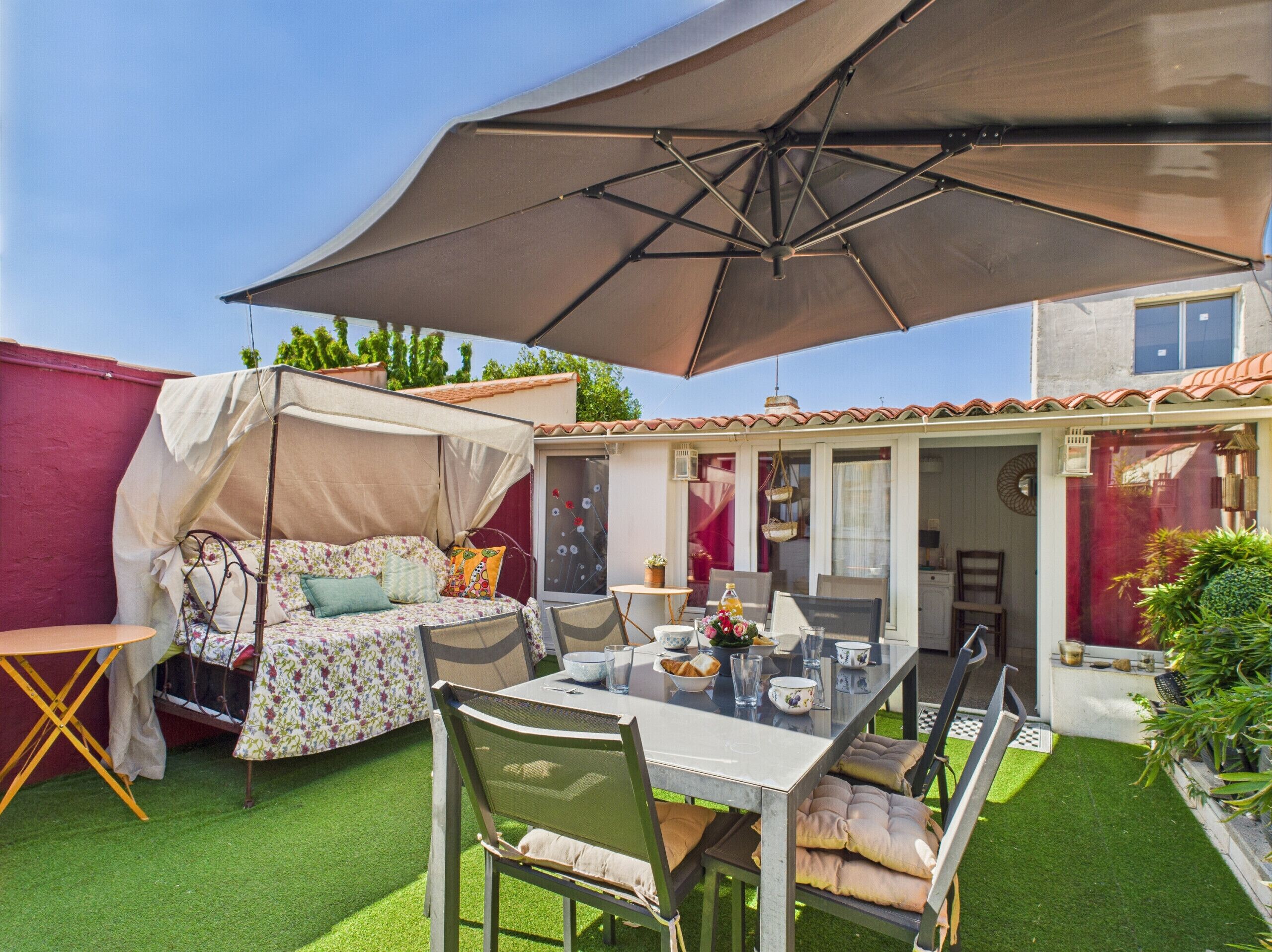 Une terrasse avec une table, des chaises, un auvent et un lit à baldaquin.