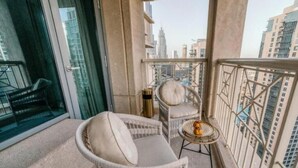 A balcony with wicker furniture, a small table, and a view of the cityscape. - Bellavista - Spacious -1BR & Extra Room  (Dubai)