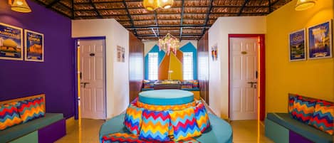 Uma área de estar vibrante e circular, com almofadas coloridas em zigue-zague, teto com design de metal ondulado e um lustre central.