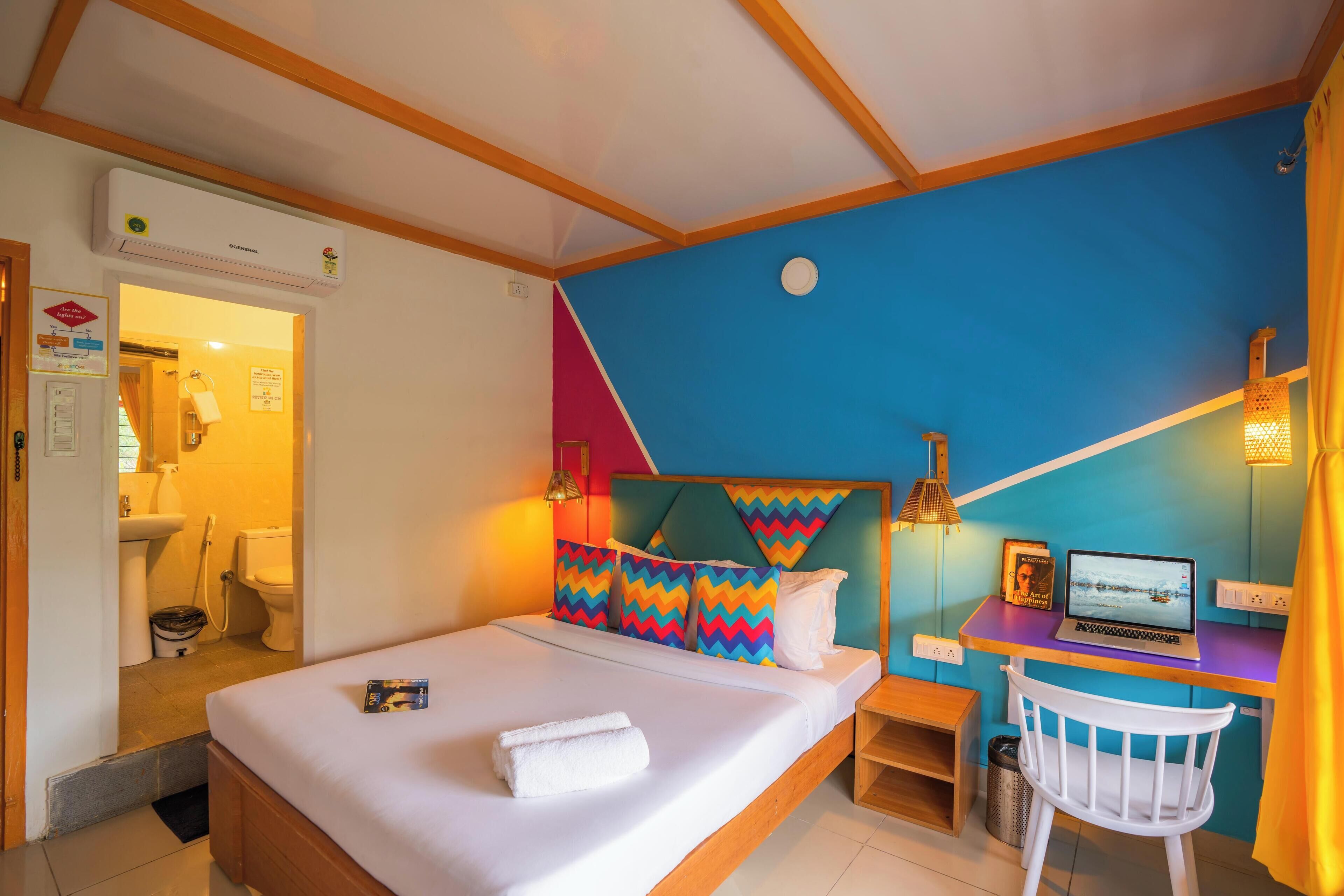 Une chambre à coucher avec un lit, un bureau avec un ordinateur portable et une chaise.