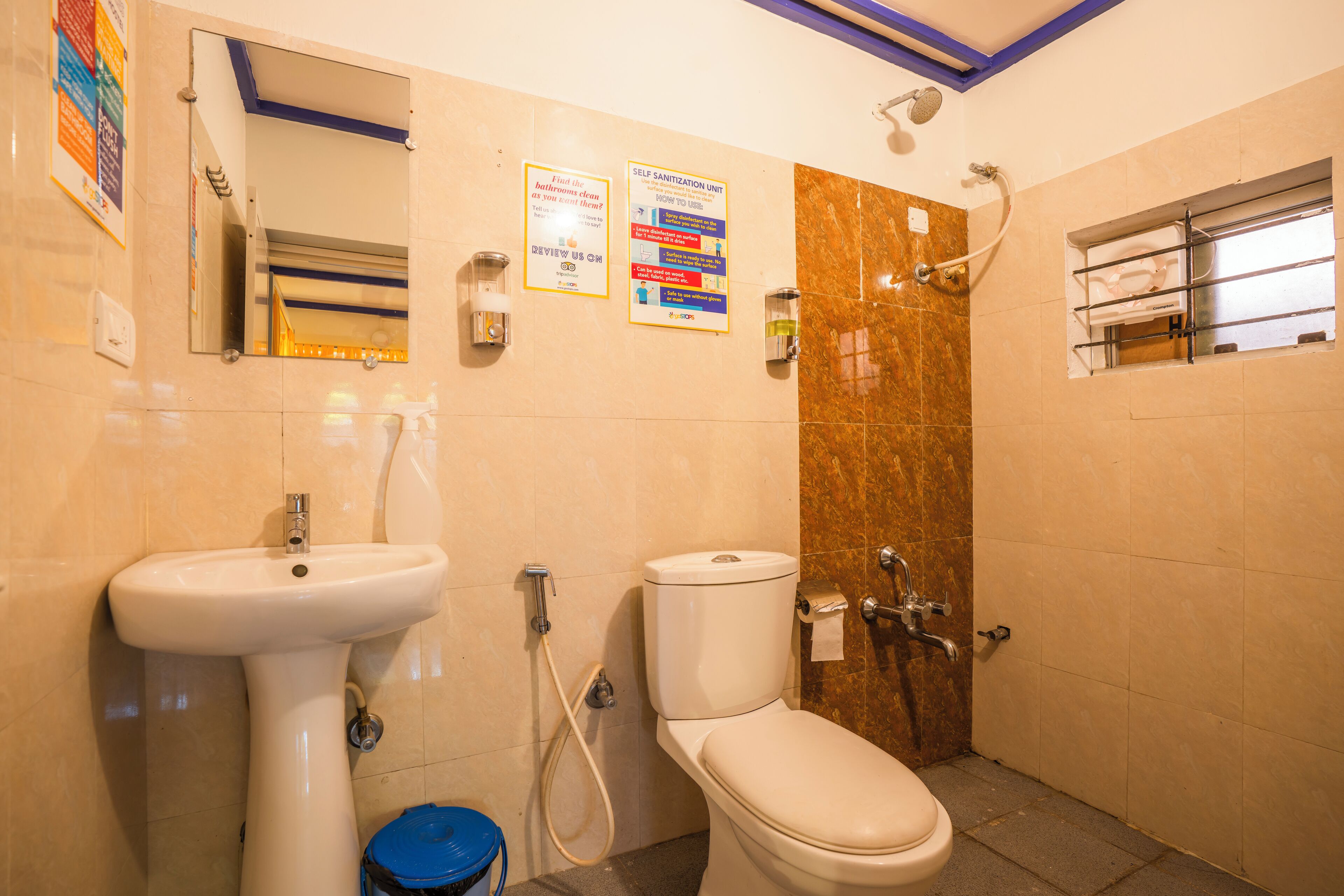 A bathroom with a sink, toilet, and shower. There are two posters on the wall, one about handwashing and the other about the self-sanitization unit.