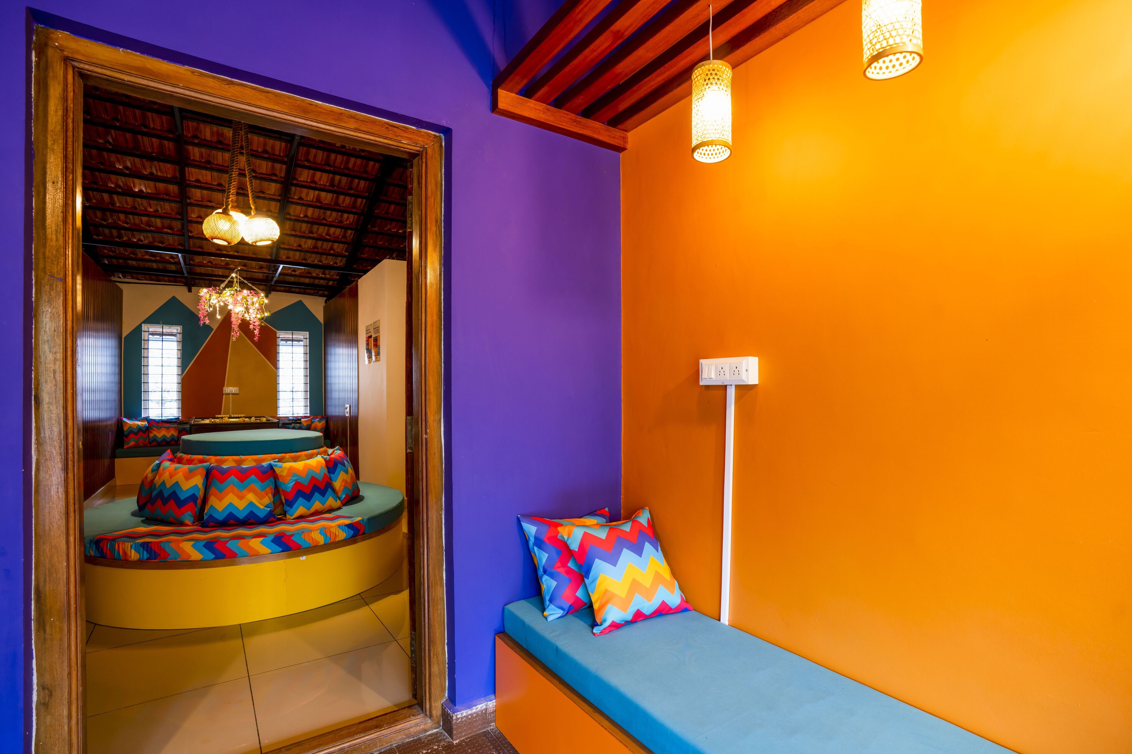 A room with a curved bench, colorful pillows, and a hanging light fixture.
