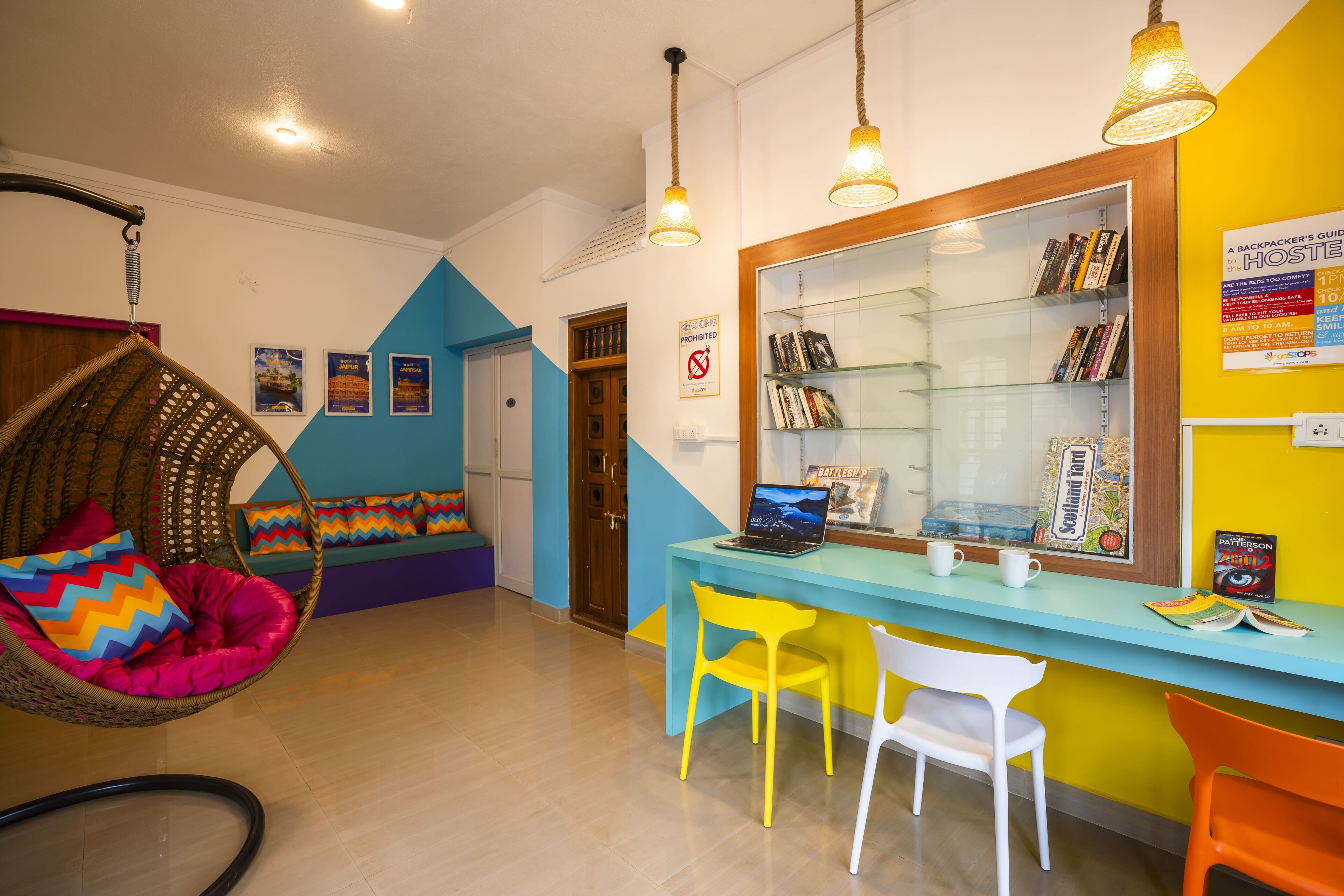 Una habitación con una silla colgante, un escritorio con sillas, una estantería y una puerta.